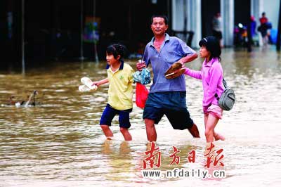樂(lè)昌市政府前和街道被水浸,一位家長(zhǎng)帶著孩子涉水而行。　　谷立輝童銅韶朱裕超攝