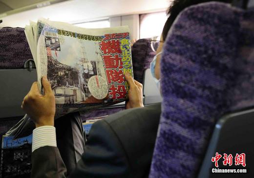 3月17日下午，在一列前往東京的新干線列車上，一名日本人在閱讀關于福島核電站三號機組最新狀況的報道。中新社發 侯宇 攝