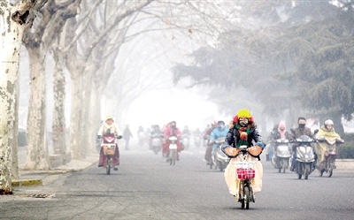昨天上午，中原路，行人在霧霾中騎車出行，很多行人戴上了口罩。