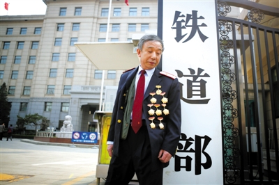 3月14日，鐵道部大門口，一位胸前掛著多枚勛章的鐵道部老職工與鐵道部牌子合影。 新京報記者 侯少卿 攝
