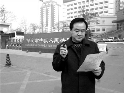 焦占軍在法院門口拿著決定書，無語站立。京華時報記者孫思婭攝
