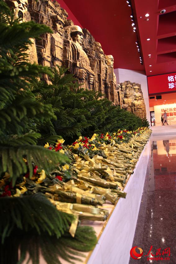 紀念館門廳的《銅墻鐵壁》雕塑墻，和人們獻上的花。邱越攝